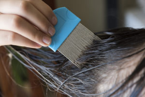 Woman applying a head lice treatment to a young girl
